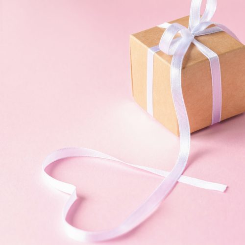 Handmade Gift or present box with white ribbon on pink background. Holiday greeting card.